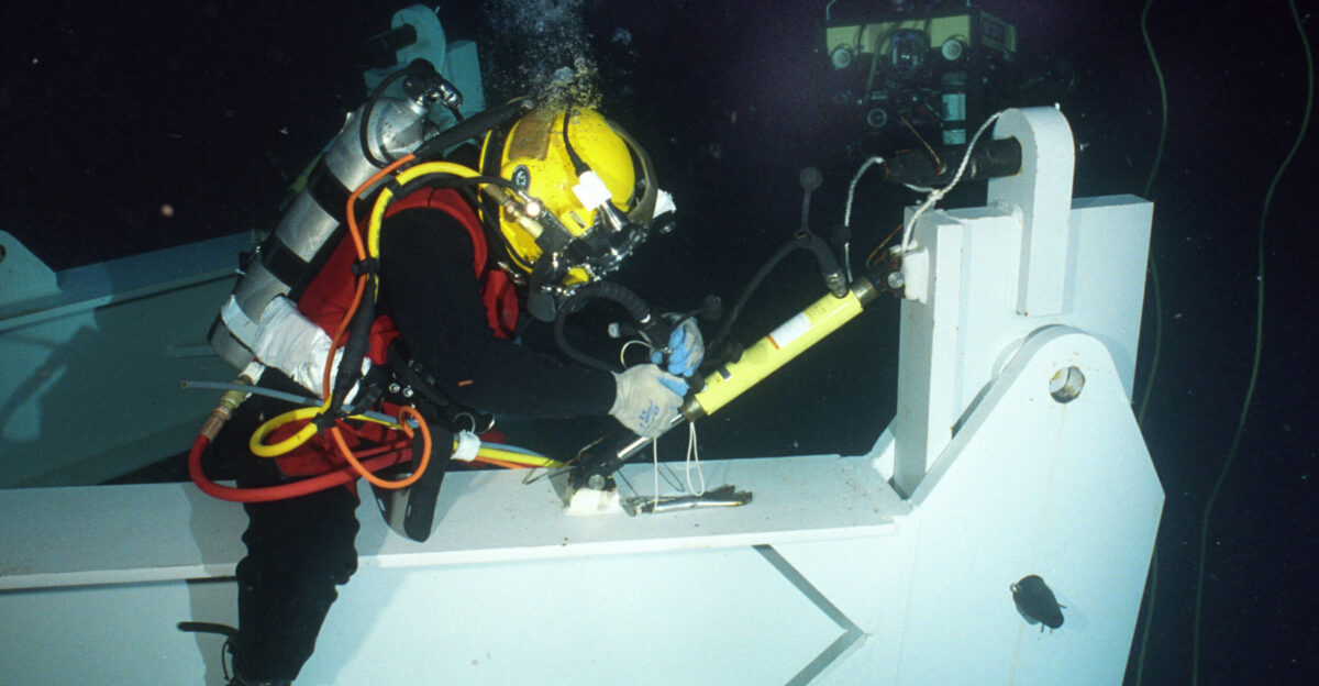 At sea off the coast of Cape Hateras N C July 21 2002 - Hull Technician 1st Class John Coffelt works on a hydraulic ram as a remote operated vehicle ROV looks on during a dive on the sunken Civil War Ironclad USS Monitor which rests 230 feet below the ocean s surface The ram will be used to articulate a leg of the spider apparatus that will lift the turret U S Navy photo by Chief Photographer s Mate Eric J Tilford RELEASED