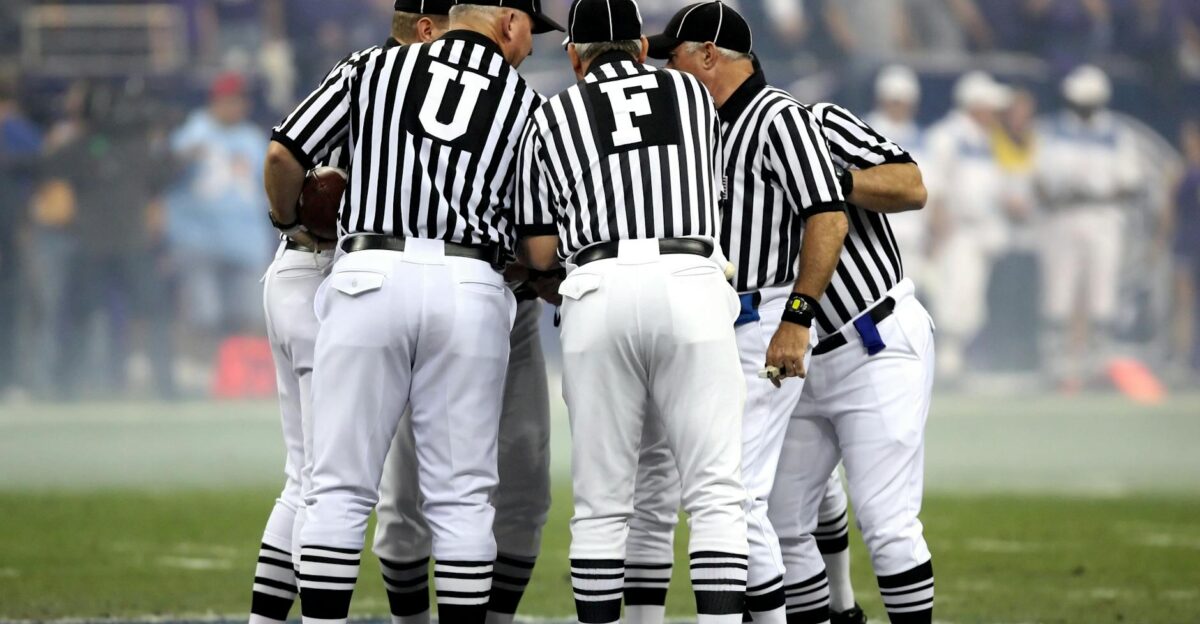 Group of sports officials in striped uniforms discussing on a football field