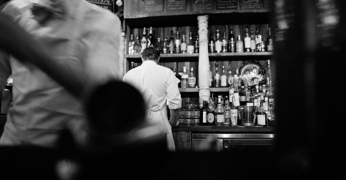 A black and white photo capturing bartenders at work in a vintage bar setting