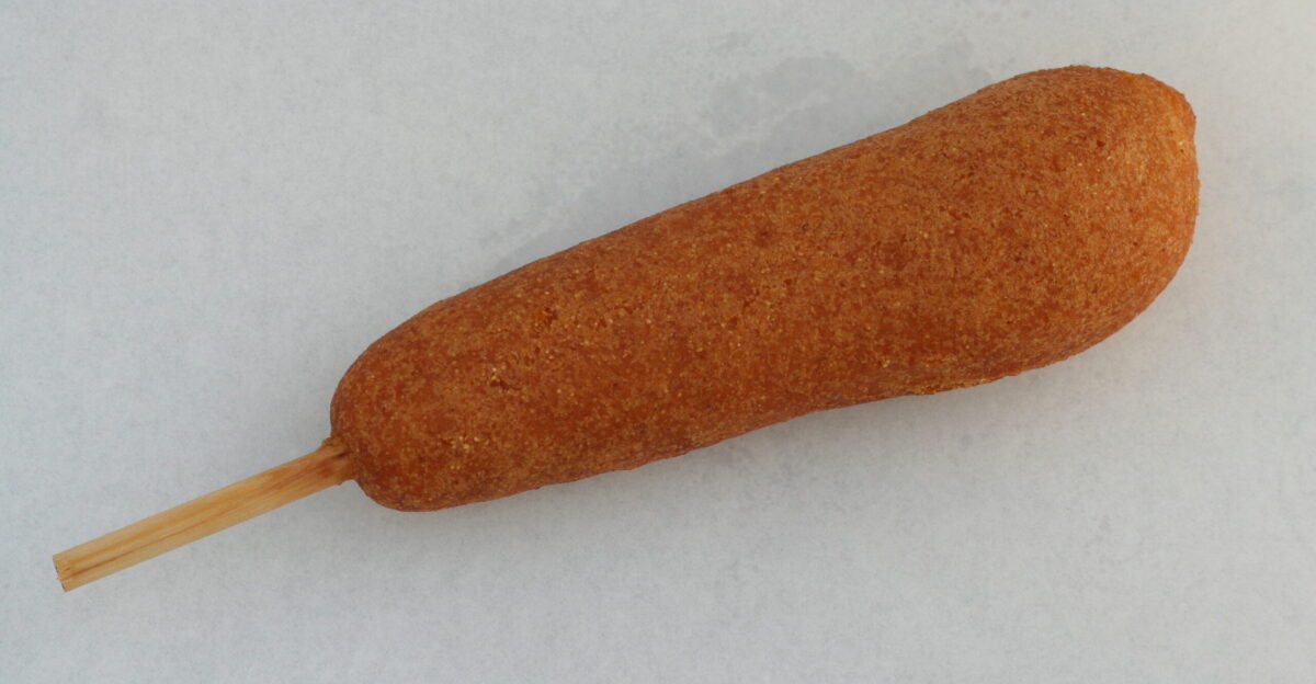 A hand-dipped corn dog on a stick served from a traveling food vendor trailer at Rochesterfest in Rochester Minnesota