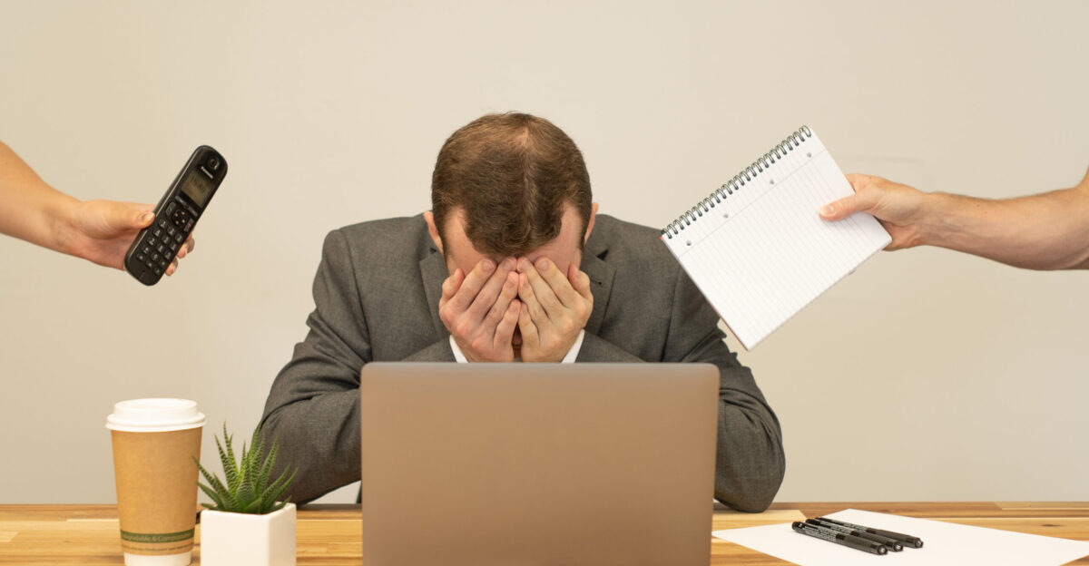A man stressed at work with a phone and notepad being passed to him This image is licensed under the Attribution Creative Commons licence which means you can use it as long as you credit us by linking to our website at ciphr com