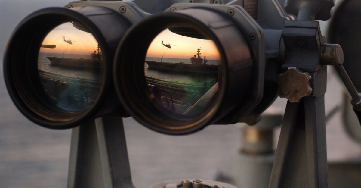 The sun sets over a set of Big Eyes binoculars on the signal bridge of the USS Harry S Truman while an MH-60S Seahawk assigned to the Bay Raiders of Helicopter Combat Support Squadron 28 airlifts several replenishment slings to the USS Dwight D Eisenhower Nov 4 2005 The Truman is under way off the coast of the eastern United States
