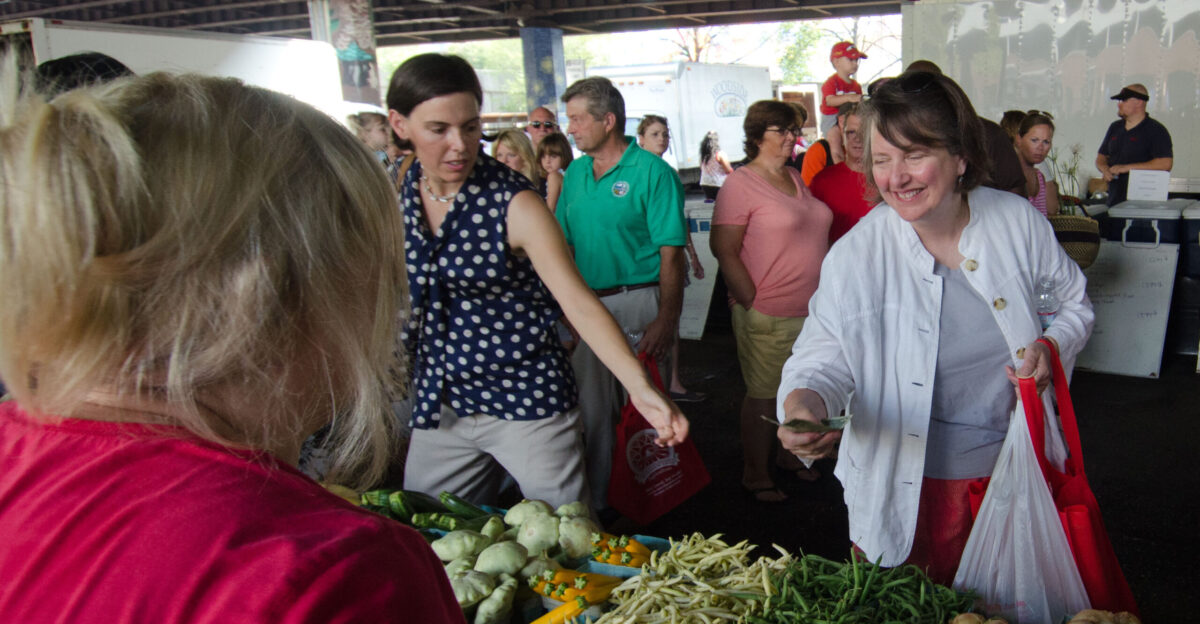 Agriculture Deputy Secretary Kathleen Merrigan right pays Michelle Kadlec left for green beans and cucumbers at Baltimore s Farmers Market and Bazaar in Baltimore MD on Sunday July 8 2012 The new wireless portable terminals at the welcome center accept the U S Department of Agriculture s USDA Food Nutrition Service s FNS Supplemental Nutrition Assistance Program SNAP Electronic Benefits Transfer EBT cards Baltimore Bucks and debit cards utilizing a wireless connection SNAP participation at farmers markets helps provide fresh fruit and vegetables to families and expands the customer base for local farmers in the Delmarva area a win-win for agriculture and local communities said Agriculture Deputy Secretary Kathleen Merrigan And when we couple SNAP access at farmers markets with strategies like education cooking demonstrations and community support in the Baltimore area consumption of healthy foods has potential to grow even more USDA Photo by Lance Cheung