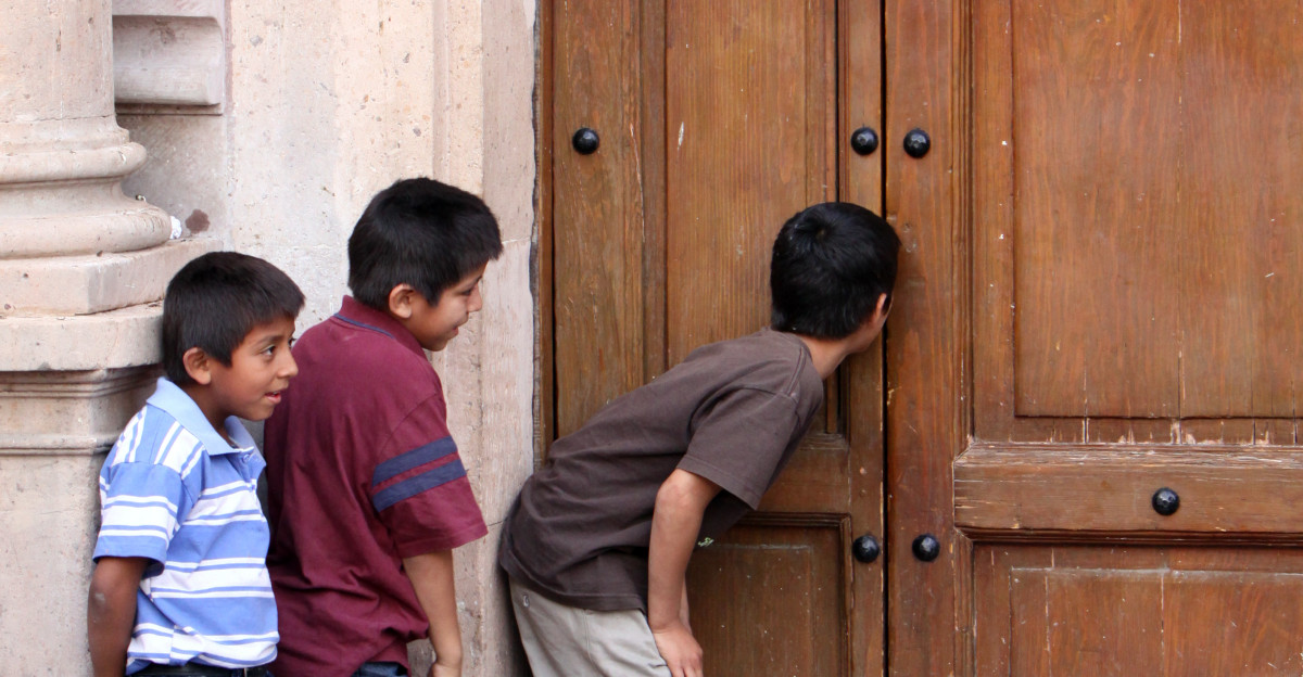 Children peeping though a church door in Mexico