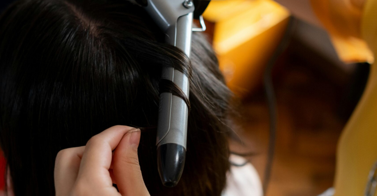 Close-up of a hairdresser curling a client's brown hair in a salon, showcasing hairstyling skills.