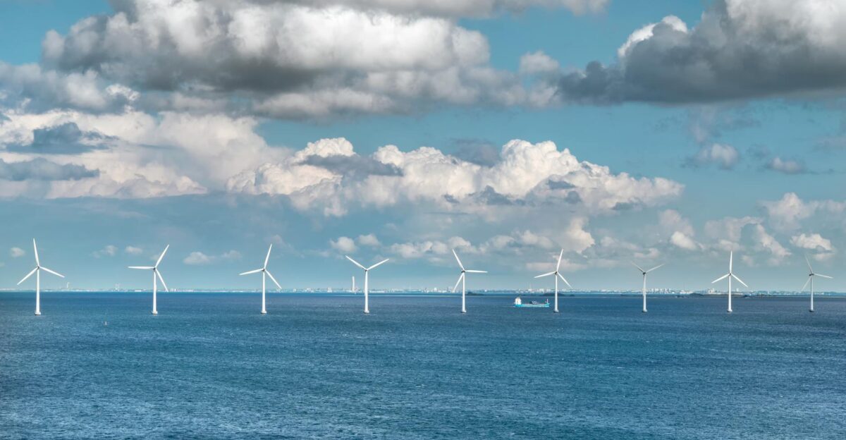 A serene view of offshore wind turbines generating renewable energy under a blue sky with scattered clouds