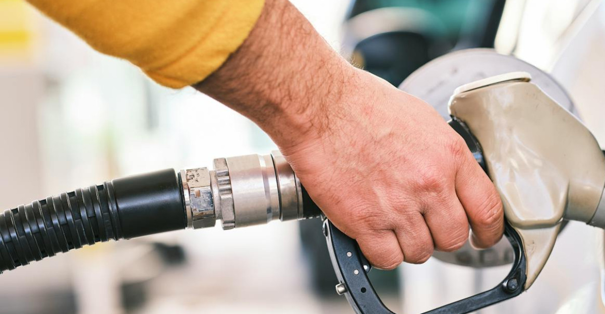Close-up of a person refueling a car with a gas nozzle at a station
