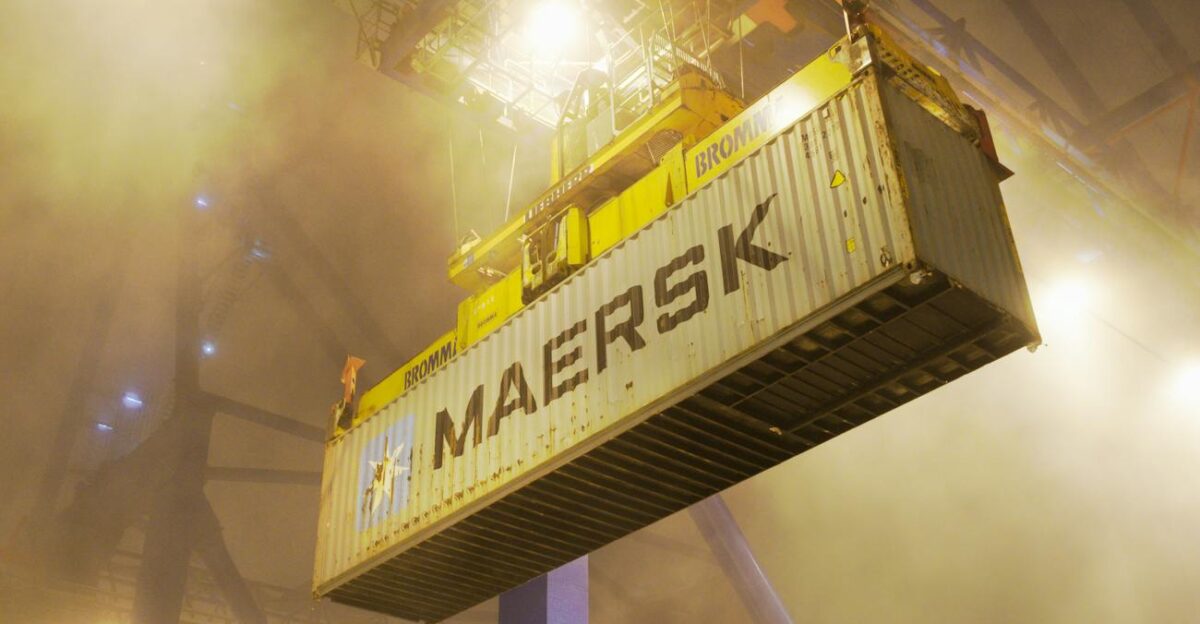 Industrial shipping container suspended by crane in Gda sk port at night