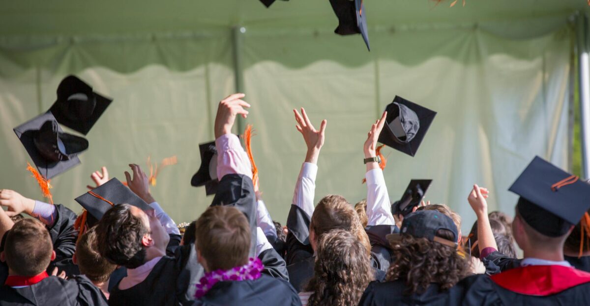 Group of graduates celebrating by tossing caps into the air during a graduation ceremony