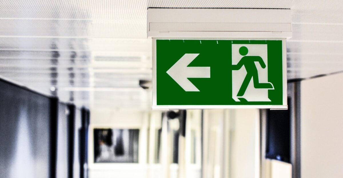Green emergency exit sign with directional arrow in a hallway