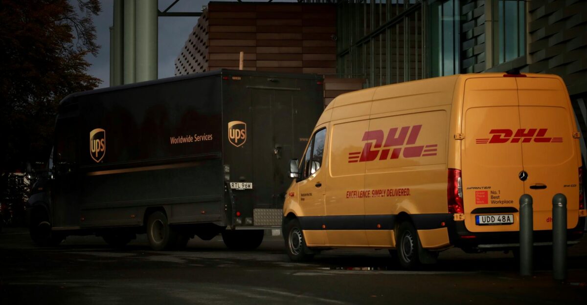 DHL and UPS delivery trucks parked at night near a modern building ready for logistics operations
