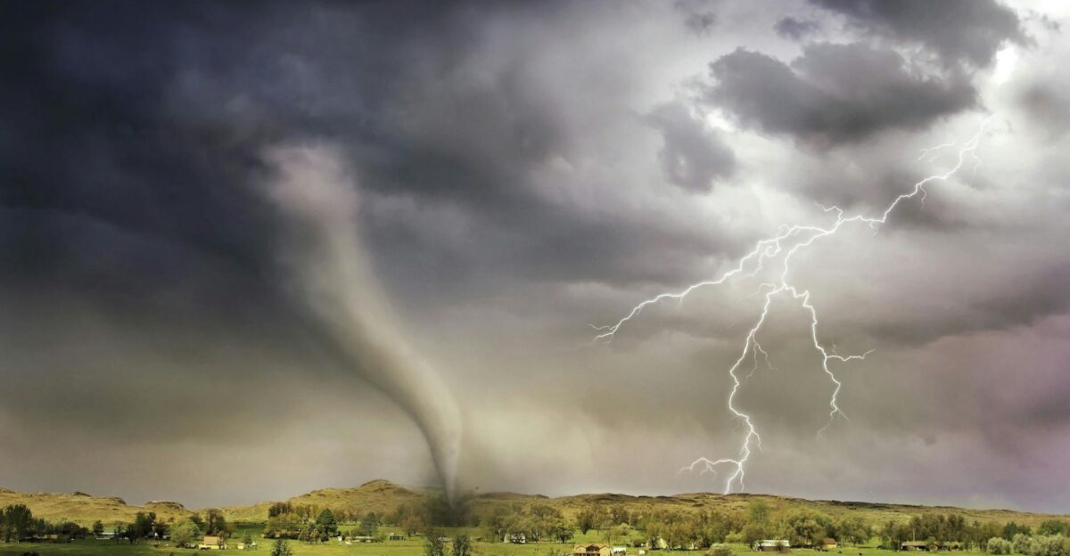 A powerful tornado and vibrant lightning striking over a rural countryside landscape
