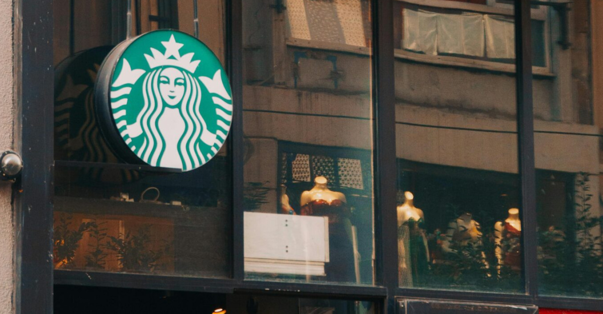 View of a Starbucks coffee shop with glass windows and signage in a bustling street.