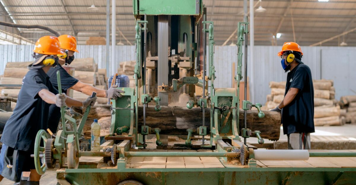 Industrial lumber processing with workers operating machinery in a factory setting