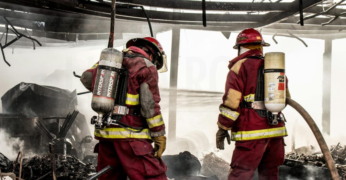 Firefighters in protective gear extinguishing flames in a charred structure