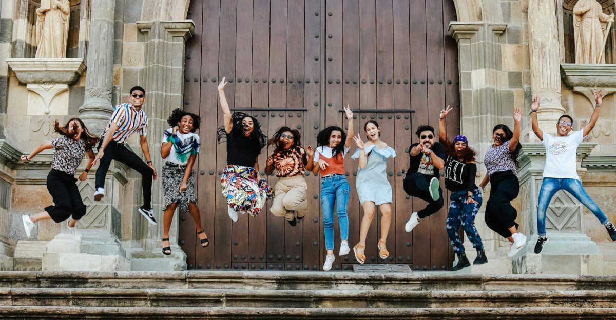 A lively group of friends joyfully jumping on steps outside a historic cathedral