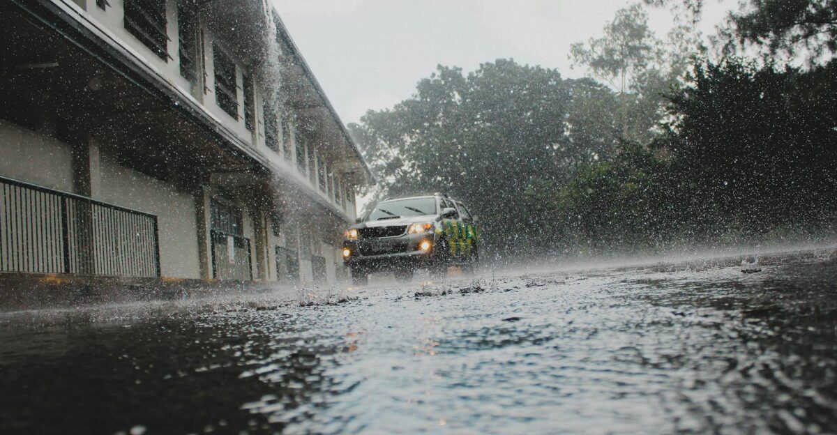 A car navigates a flooded street amid heavy rain and stormy weather