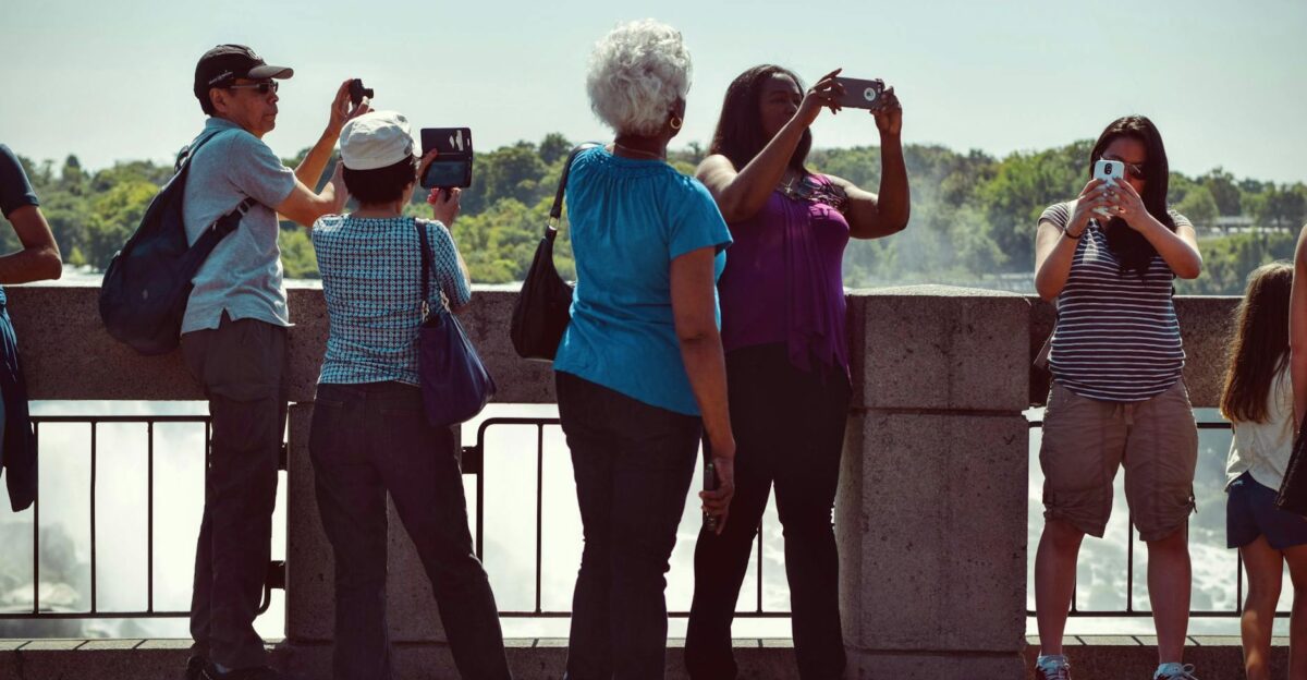 Group of diverse tourists using smartphones to capture scenic outdoor views on a sunny day