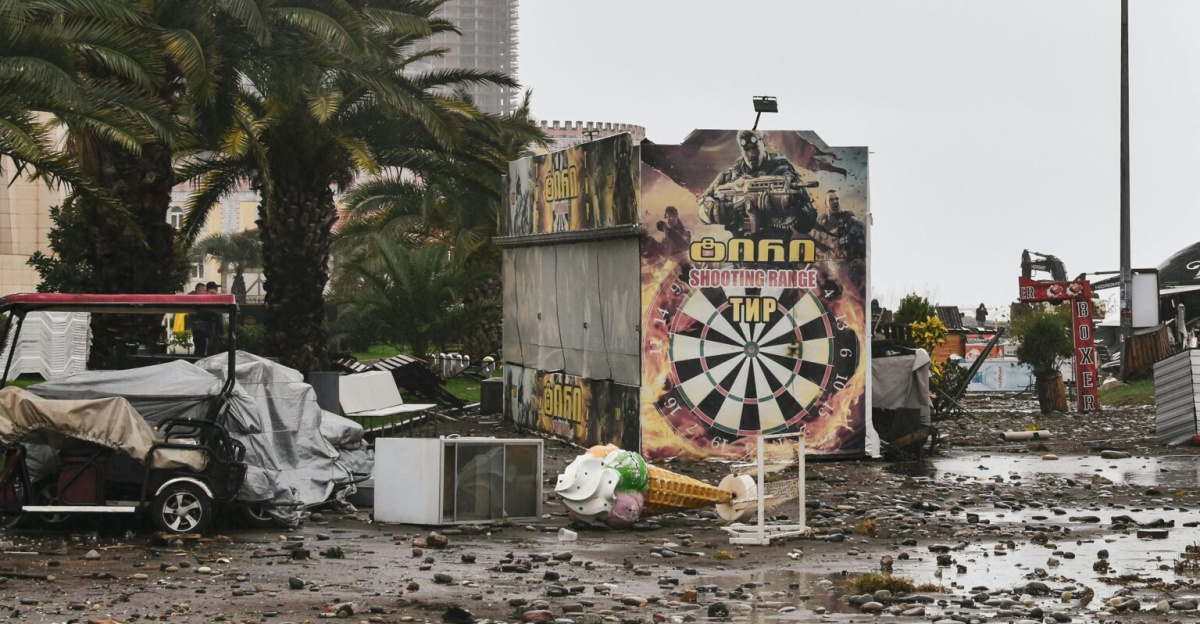 City street filled with storm debris and damaged structures under a cloudy sky.