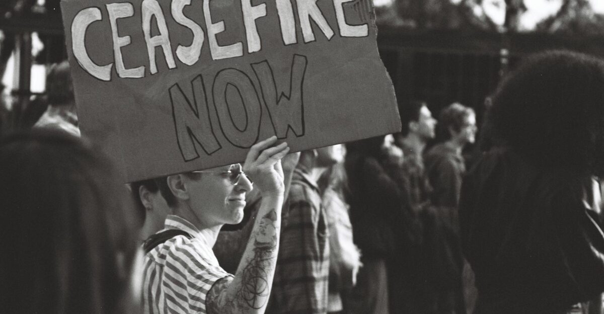 Black and white photo of a protest in Lisbon with a person holding a Ceasefire Now sign