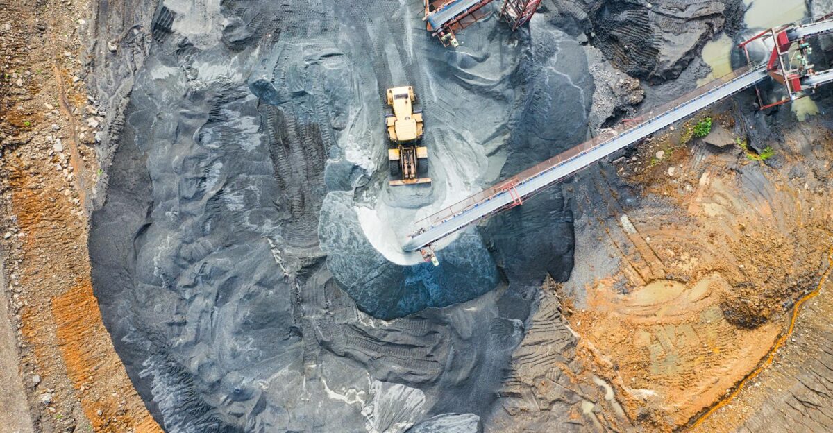 Aerial view of a large industrial mining site with heavy machinery and conveyor belts in operation