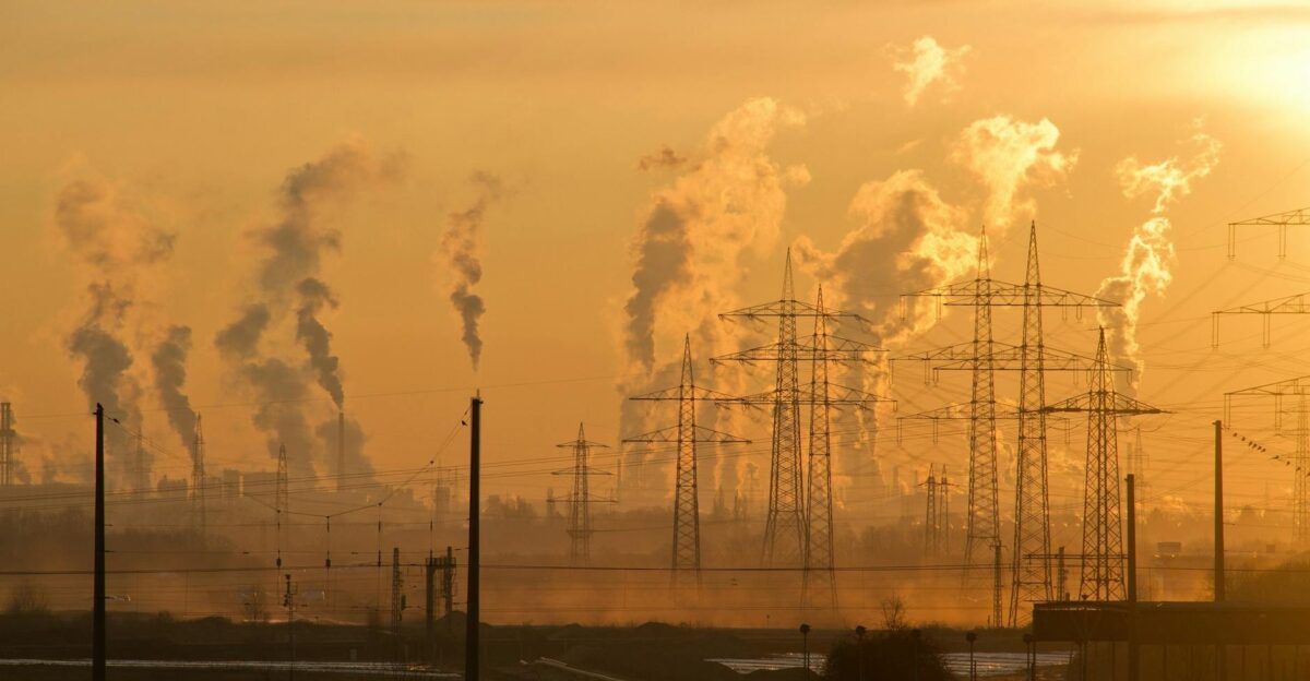 Silhouette of power lines and industrial smoke at sunset highlighting pollution and energy themes