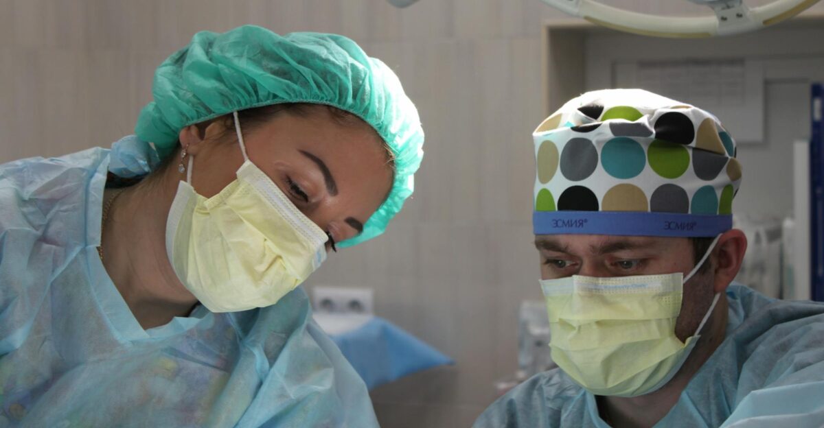 Surgeons wearing masks and scrubs conduct an operation in a hospital setting