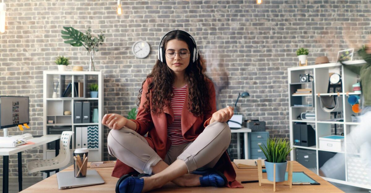Young woman meditating with headphones in a modern office setting practicing mindfulness