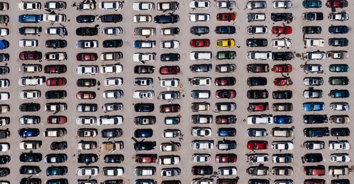Top-down aerial shot of a large parking lot filled with rows of cars showcasing organized symmetry