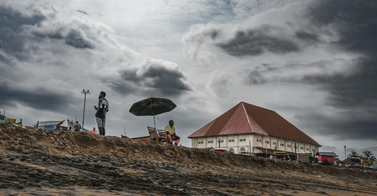 A stormy beach scene with people and a distinct building showcasing dramatic clouds for a moody feel