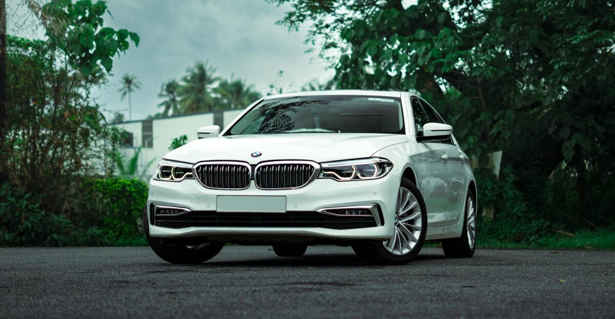 White BMW 5 Series parked on a scenic outdoor road showcasing luxury and elegance