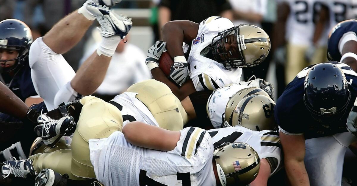 Intense action scene of football players tackling during a game showcasing teamwork and sportsmanship