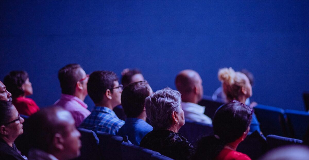 An attentive group of adults seated at an indoor conference focusing on a presentation