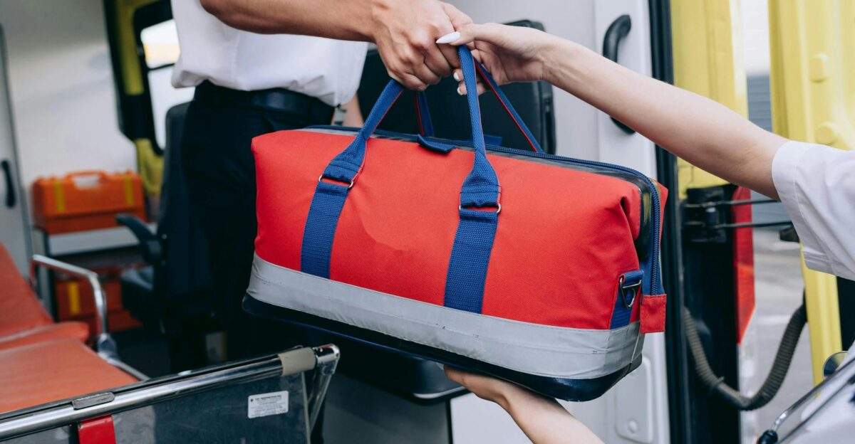 Paramedics exchanging a red medical bag inside an ambulance demonstrating teamwork