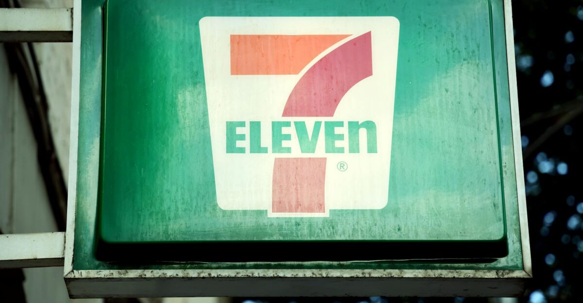 A close-up of a 7-Eleven store sign in a city environment outdoors