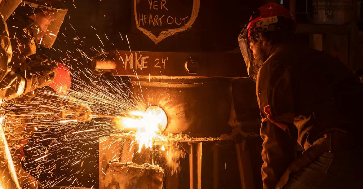 Industrial workers pouring molten metal with sparks flying in Milwaukee workshop