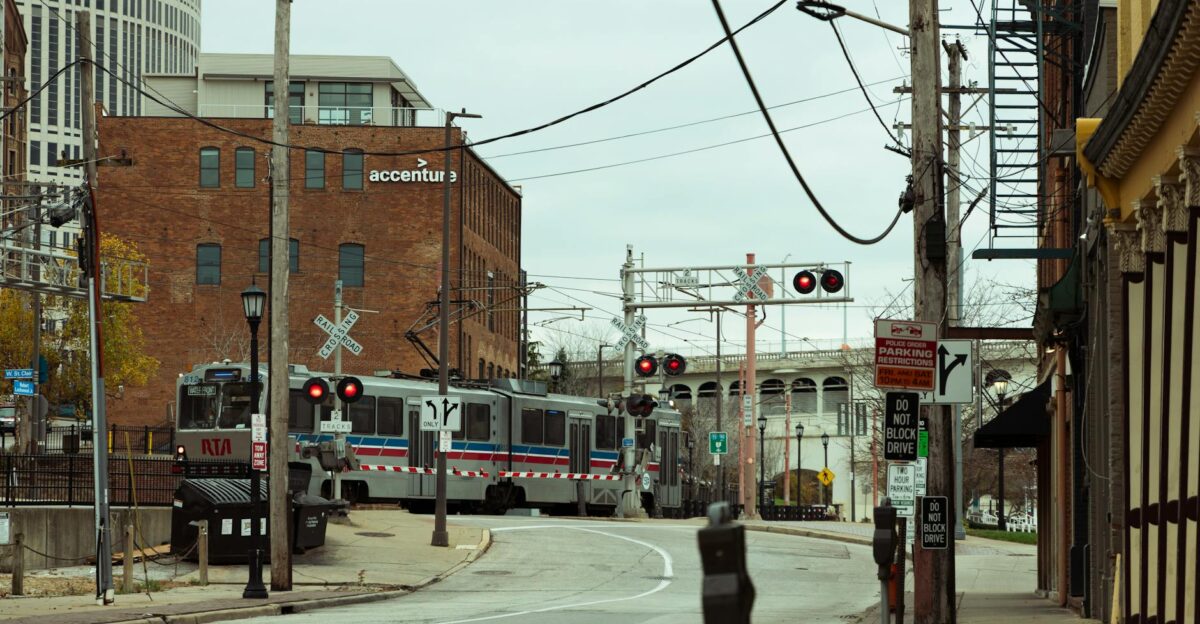 A city train crosses an urban street near a recognizable business landmark