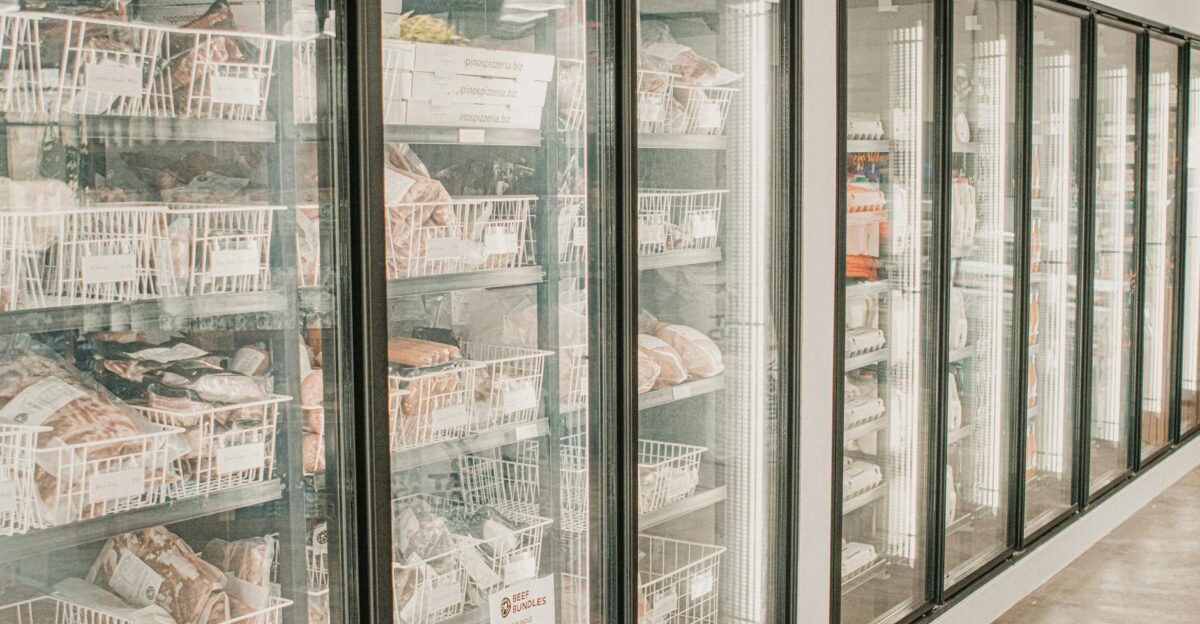 Frozen meats in a retail freezer with transparent doors and organized sections