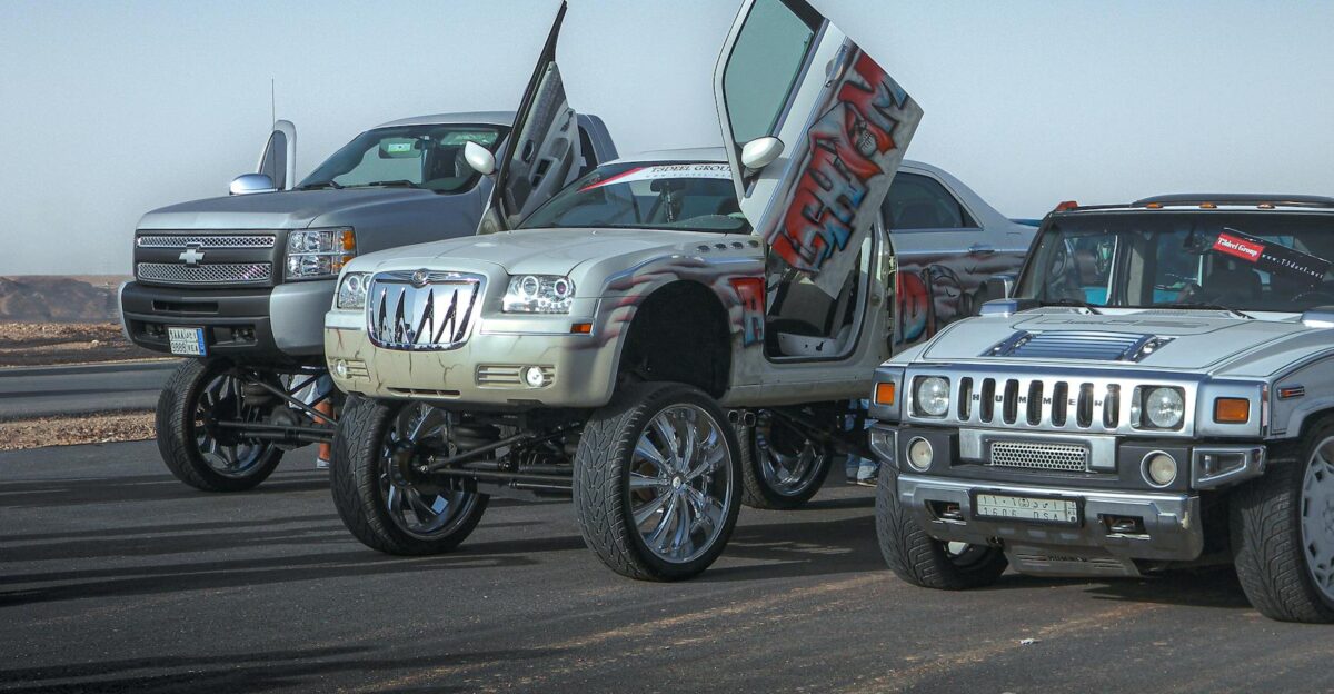 Modified cars including a Chrysler C300 and Hummer H1 in Riyadh desert showcasing customization and desert aesthetics