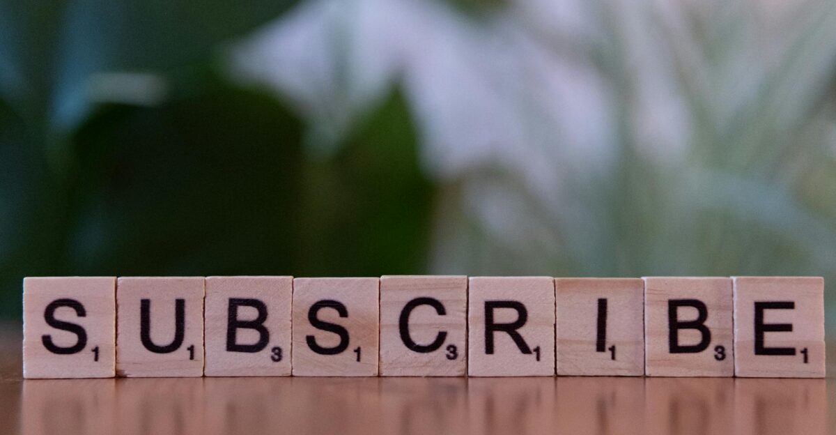 Close-up of the word SUBSCRIBE spelled with wooden letter tiles on a table