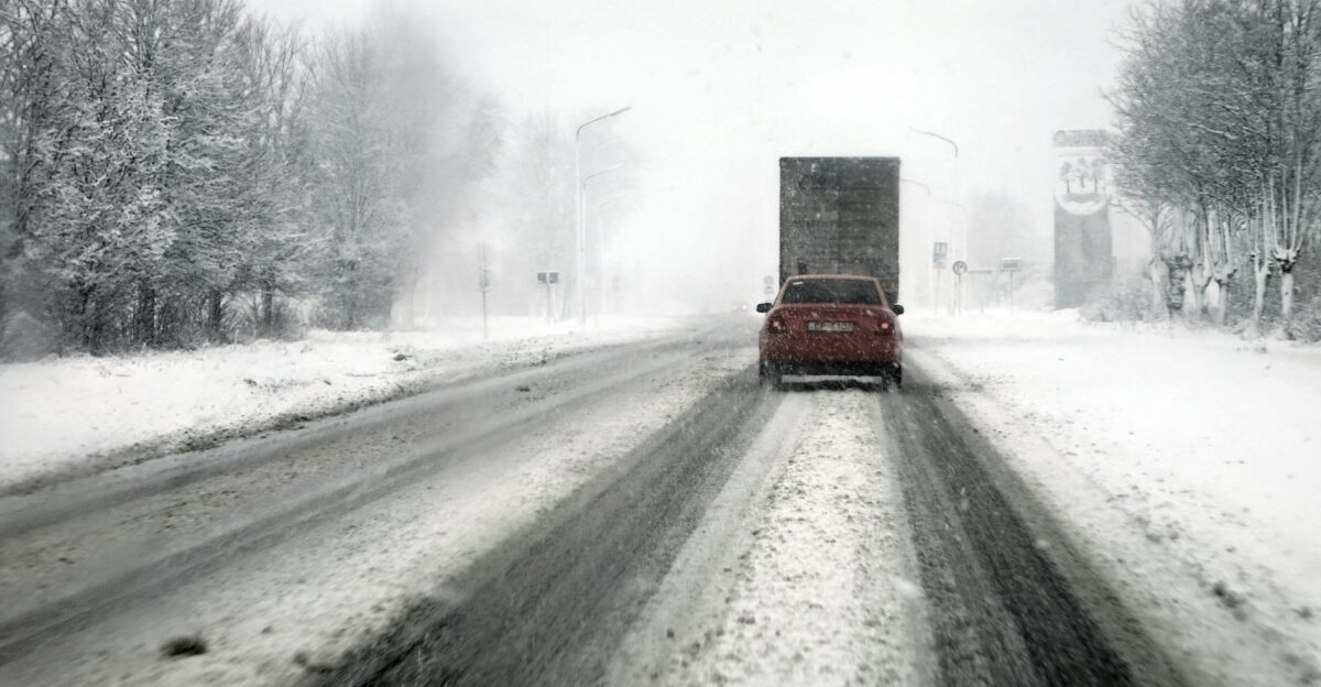 Cars navigate a snowy highway during a blizzard showcasing tough winter driving conditions