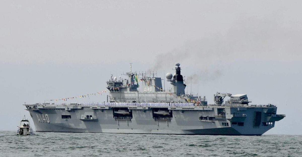 Military aircraft carrier sailing on ocean with visible smoke
