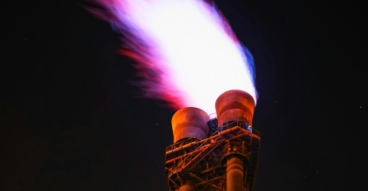 Dramatic night photo of gas flare on industrial facility emitting a powerful flame.