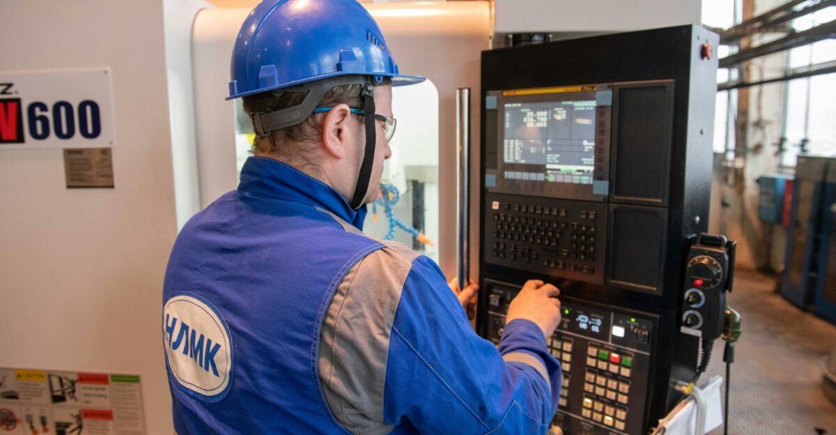 Russian factory worker in blue uniform operating CNC machine indoors