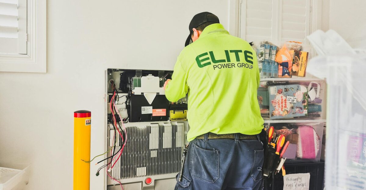 A technician from Elite Power Group installing a home battery system indoors in New South Wales Australia