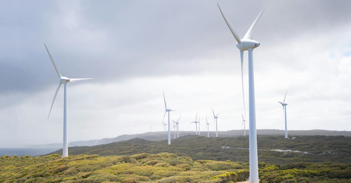 Majestic wind turbines harnessing energy in a vast green landscape under cloudy skies
