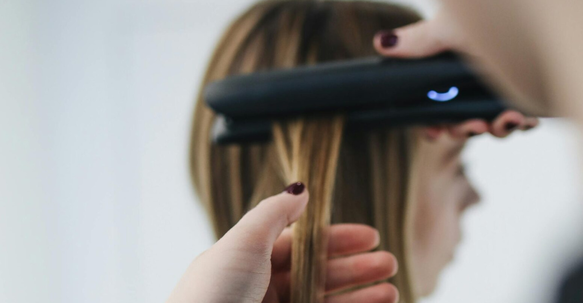 Close-up shot of a hairstylist straightening hair in a salon setting.