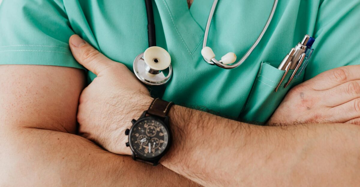 Close-up of a healthcare professional with arms crossed wearing medical scrubs and stethoscope