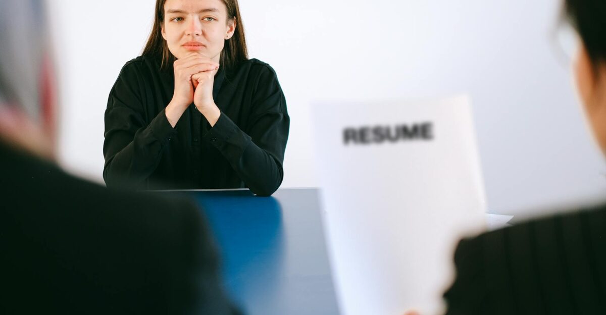 A woman in a job interview facing two employers with a focus on her resume