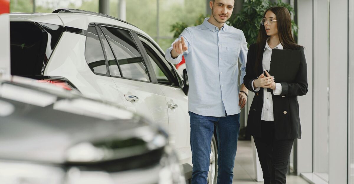 Customer and salesperson discussing a vehicle inside a modern car dealership showroom